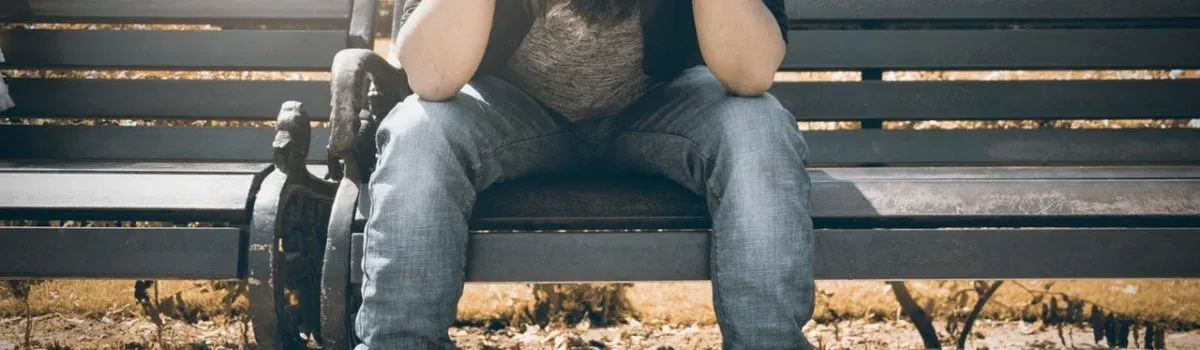 A young person sitting alone looking at a phone